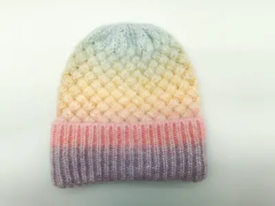 Handgestrickte Mütze mit sanftem Farbübergang von Lavendel über Rosa und Gelb bis zu Himmelblau, mit Korbgeflecht-Muster und Rippenbund