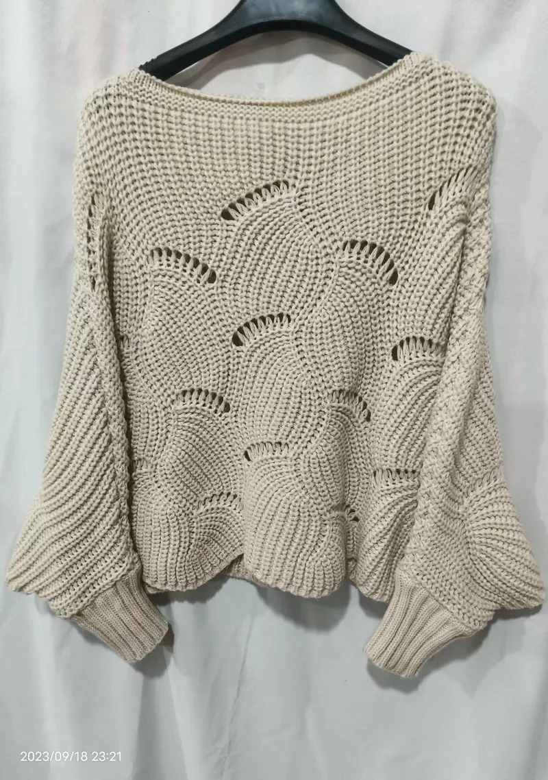 Cremefarbener weiter Häkel-Strickpullover mit dekorativem Fächerstich und ausgestellten Ärmeln auf einem Kleiderbügel