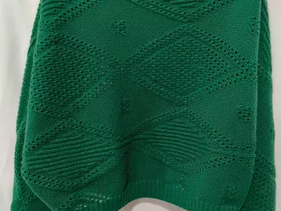 Rückenansicht eines smaragdgrünen Oversize-Strickpullovers mit Rautenmuster-Lochdurchbrüchen und Rippenbund auf Schneiderpuppe