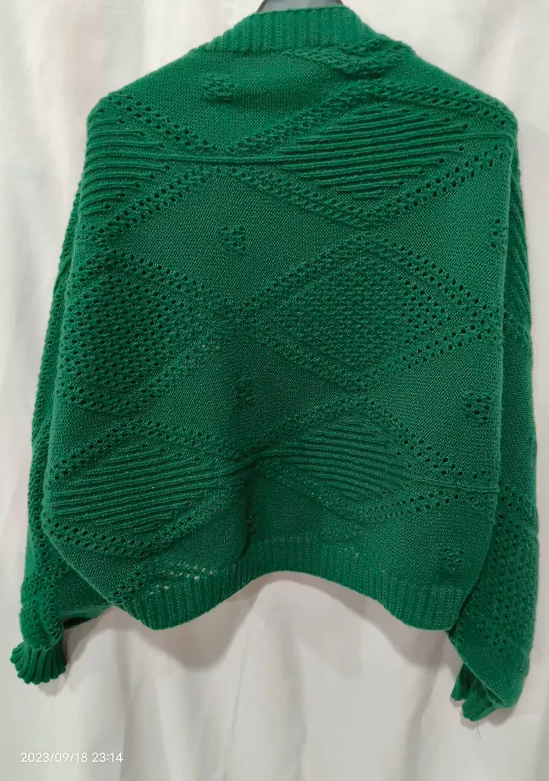 Rückenansicht eines smaragdgrünen Oversize-Strickpullovers mit Rautenmuster-Lochdurchbrüchen und Rippenbund auf Schneiderpuppe
