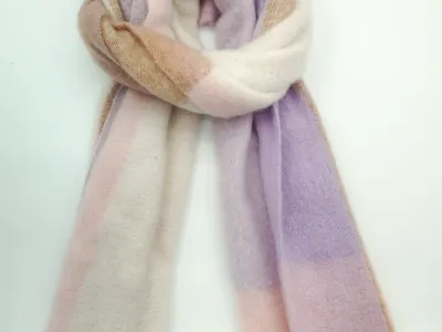 Aufgerollter Mohair-Mischschal mit sanften Farbblöcken in Lavendel, Zartrosa, Creme und Kamel auf weißem Hintergrund