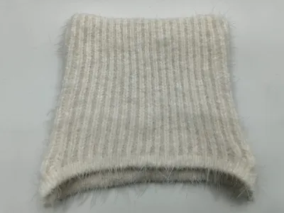 Nahaufnahme eines cremebeigefarbenen Rippenstrick-Stoffmusters mit weichem Mohair-Heiligenschein-Effekt, flach gefaltet auf weißem Hintergrund