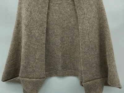 Taupefarbene beige Pointelle-Strick Schulterjacke mit offenem Vorderteil, Rautenspitzenmuster und gerippten Bündchen auf einem Kleiderbügel