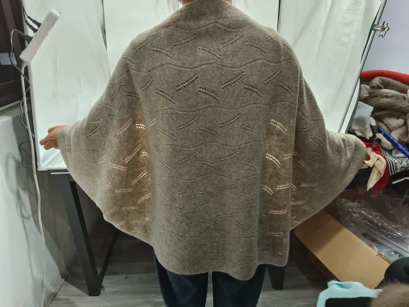 Rückenansicht einer Frau in einem übergroßen beigen Pointelle-Strick Cardigan mit Fledermausärmeln und Wellenmuster-Spitzenstrick