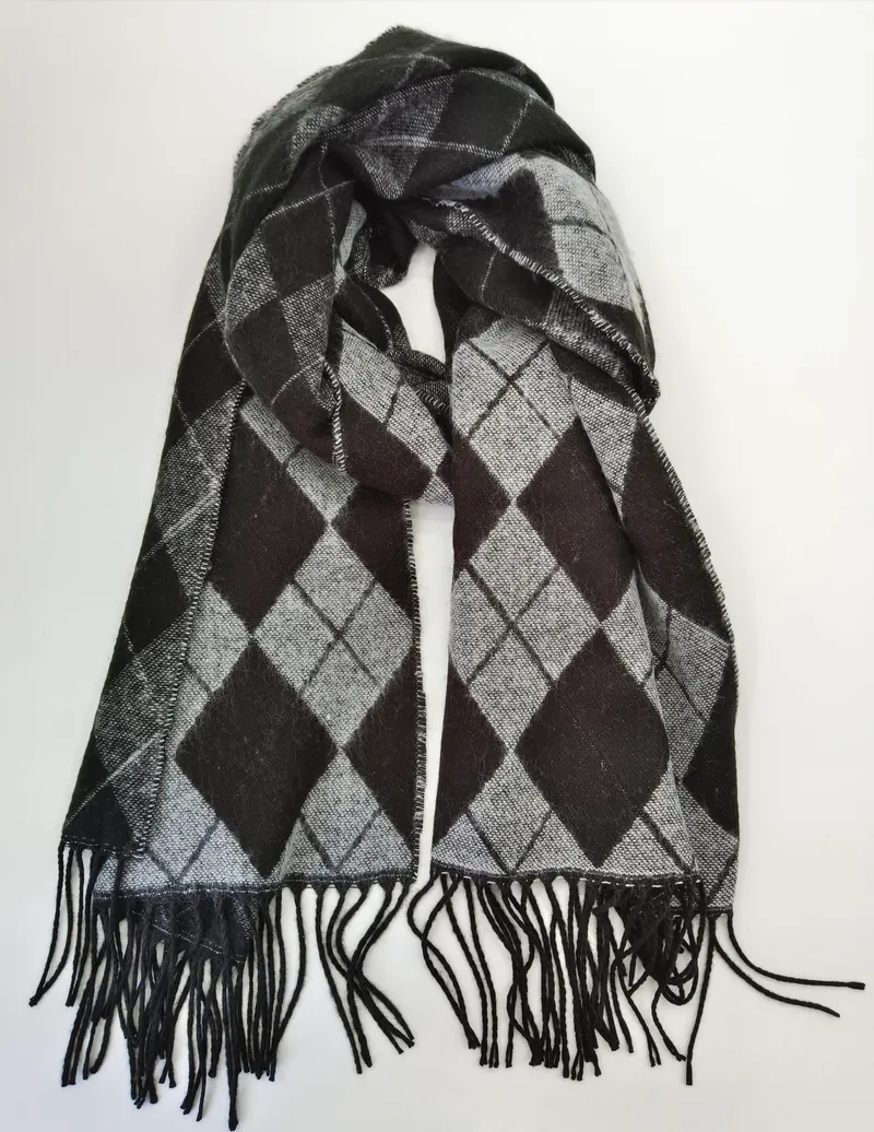 Gestrickter Winterschal in Schwarz und Grau mit klassischem Rautenmuster und langen schwarzen Fransen, flach auf weißem Untergrund