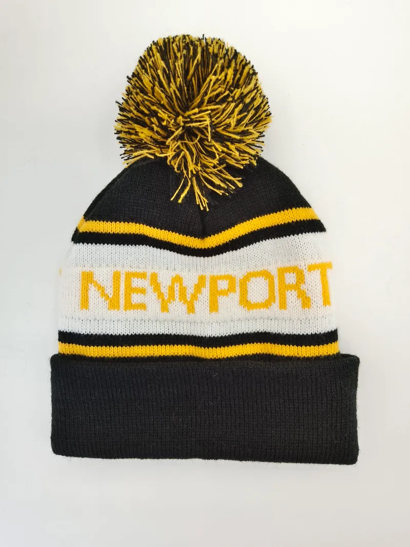 Gestreifte Strickmütze in Schwarz, Weiß und Gelb mit Newport-Schriftzug und großem zweifarbigem Bommel, freigestellt auf weißem Hintergrund