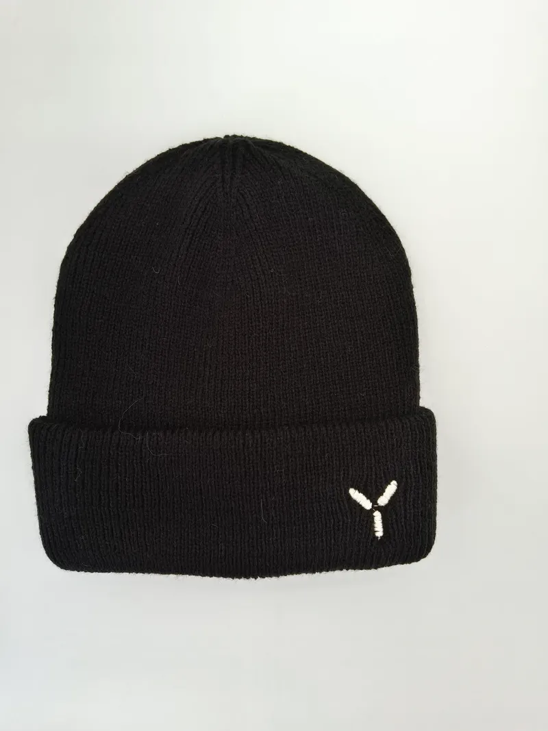 Schwarze Rippenstrickmütze mit Umschlagbündchen und kleinem weißem gestickten Y-Logo auf hellgrauem Hintergrund