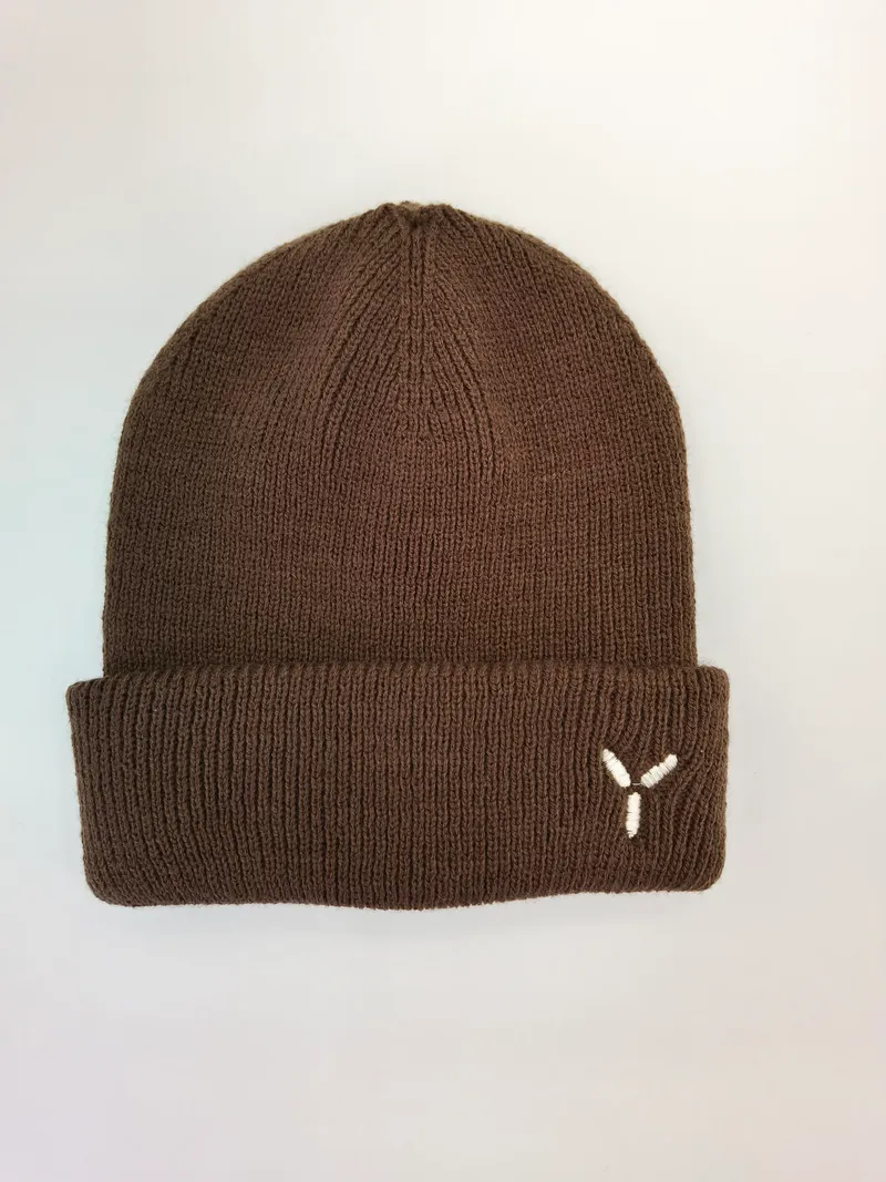 Braune Rippenstrick-Wintermütze mit gefaltetem Bündchen und kleinem weißen gestickten Logo auf hellem Hintergrund
