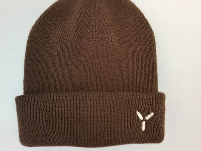 Braune Rippenstrick-Wintermütze mit gefaltetem Bündchen und kleinem weißen gestickten Logo auf hellem Hintergrund