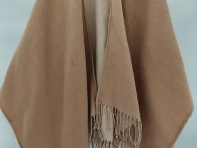 Kamelbrauner offener Wickelschal-Cape mit gedrehtem Fransenrand auf einem Kleiderbügel präsentiert