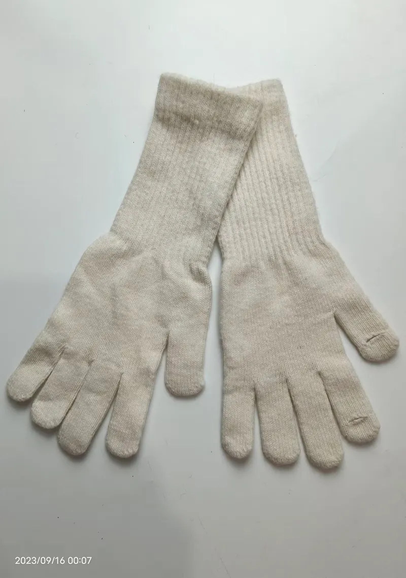 Paar cremefarbene Strick-Handschuhe mit langen Strickbündchen flach auf weißem Untergrund liegend, Handflächen sichtbar