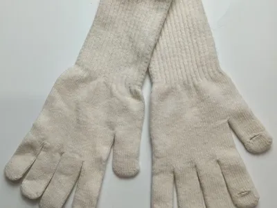 Paar cremefarbene Strick-Handschuhe mit langen Strickbündchen flach auf weißem Untergrund liegend, Handflächen sichtbar