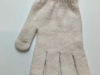 Ein einzelner cremefarbener Winterhandschuh mit geripptem Abschluss und zartem rosa Streifen-Detail, Draufsicht auf weißem Untergrund