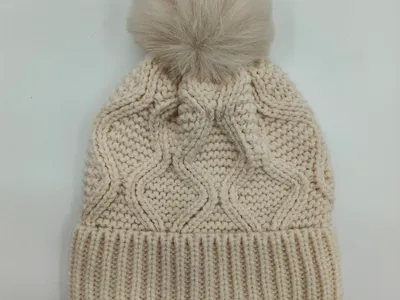 Cremeweiße Zopfstrick-Beanie mit großem flauschigem Kunstfell-Pompon oben und geripptem Bündchen