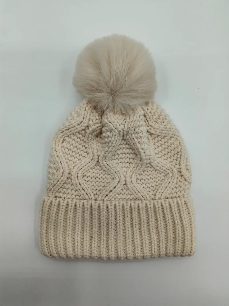 Cremeweiße Zopfstrick-Beanie mit großem flauschigem Kunstfell-Pompon oben und geripptem Bündchen