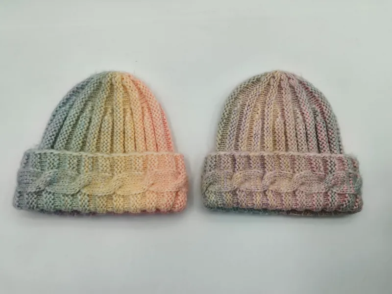 Zwei handgestrickte Beanies mit Zopfmuster-Bündchen, eine in Grün-Gelb-Pfirsich und eine in gedämpften Rosa-Taupe-Tönen