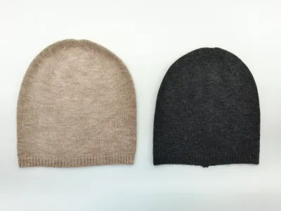 Zwei flach gelegte Kaschmir-Slouchy-Beanies nebeneinander in Oatmeal-Beige und Anthrazitgrau mit Rippenbund auf weißem Hintergrund