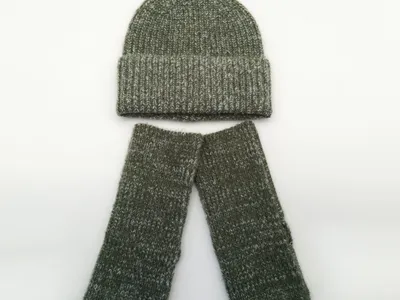 Olivgrüne melierte Rippenstrickmütze mit passenden fingerfreien Handschuhen, nebeneinander auf weißem Hintergrund