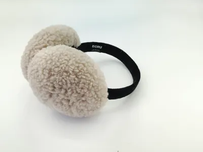 Cremefarbene Ohrenwärmer aus flauschigem Sherpa-Fleece mit schmalem schwarzen Haarband, auf hellem Hintergrund