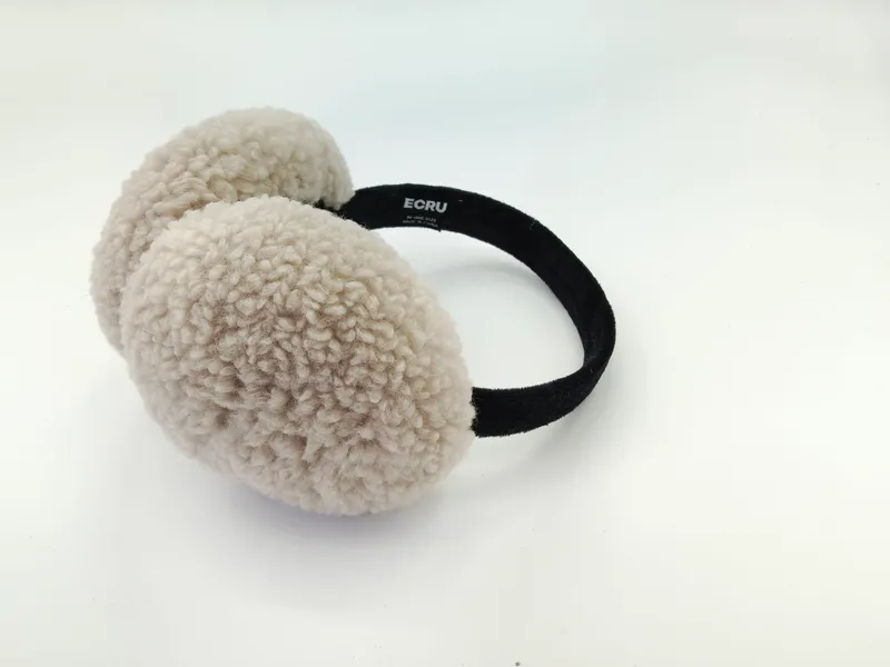 Cremefarbene Ohrenwärmer aus flauschigem Sherpa-Fleece mit schmalem schwarzen Haarband, auf hellem Hintergrund