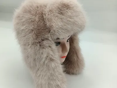 Flauschige Kunstpelzmütze in Beige im Ushanka-Stil mit langen Ohrklappen auf einem Modellkopf, seitliche Ansicht