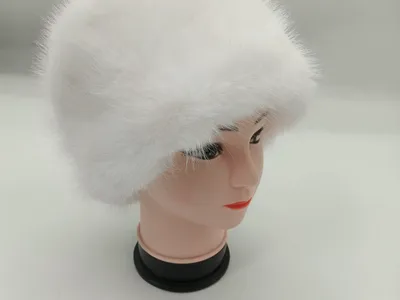 Weißer fluffiger Kunstpelzhut im Kosakendesign auf einer Hutform, vor hellgrauem Hintergrund