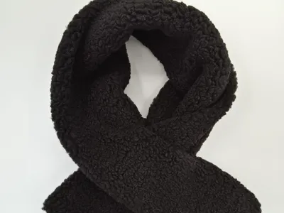 Schwarzer Teddy-Fleece-Schal in Schleifenform auf weißem Hintergrund, mit sichtbarer lockig-flauschiger Oberflächenstruktur