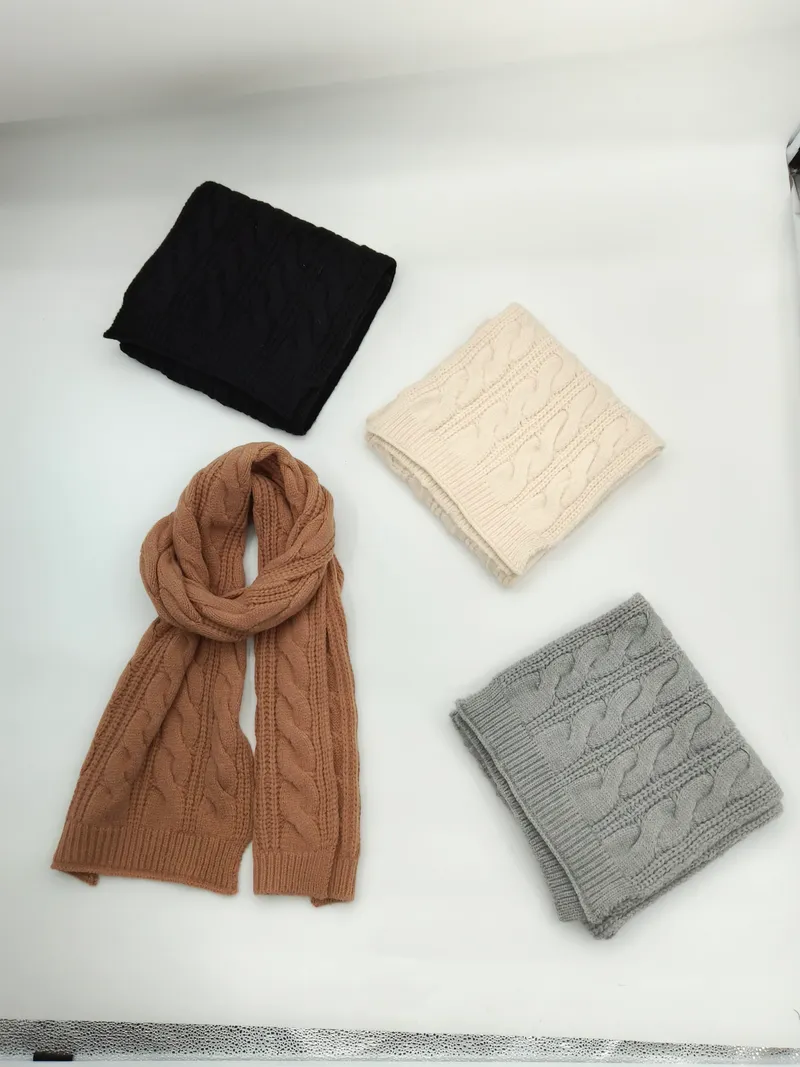 Vier gefaltete Strickschals mit Zopfmuster in den Farben Anthrazit, Elfenbein, Kamelbraun und Hellgrau auf hellem Untergrund, einer ausgebreitet in voller Länge