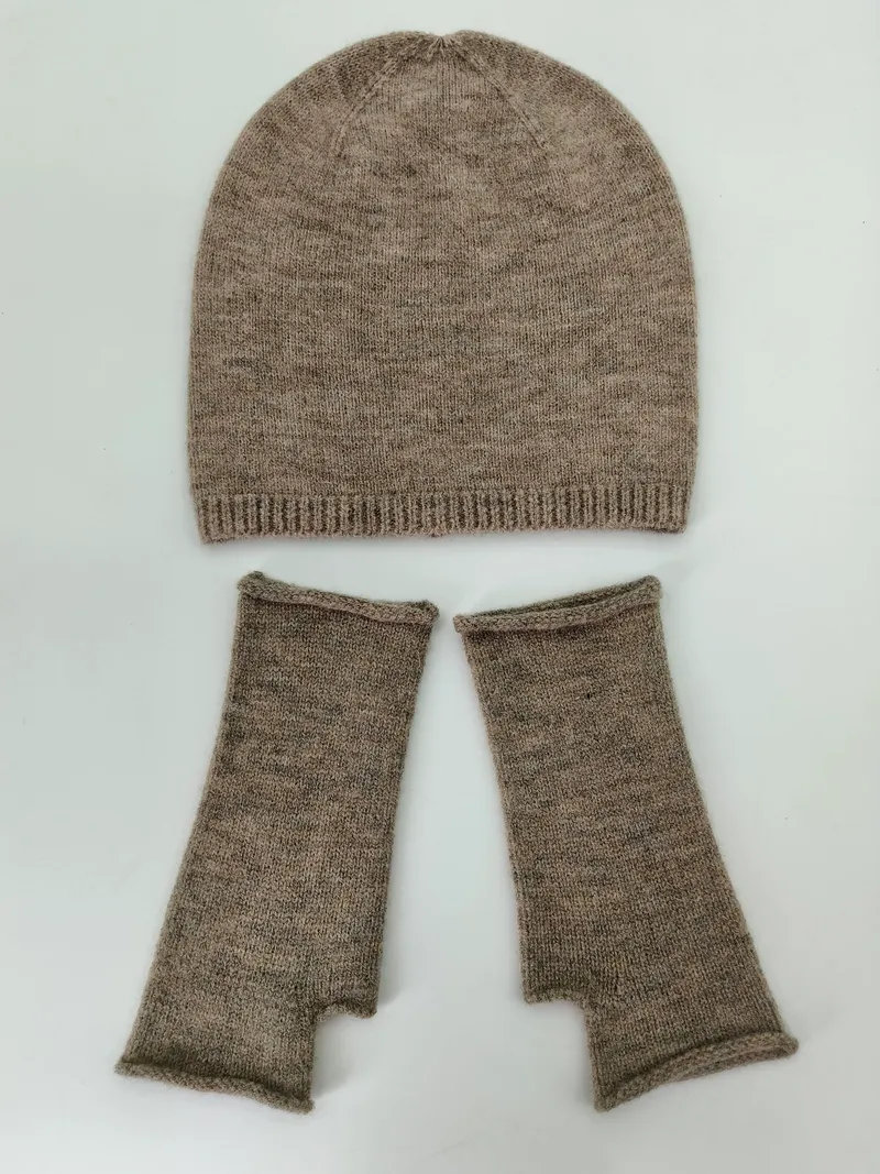 Meliertes Taupe-Beanie und passende fingerlose Strickhandschuhe flach auf weißem Untergrund arrangiert