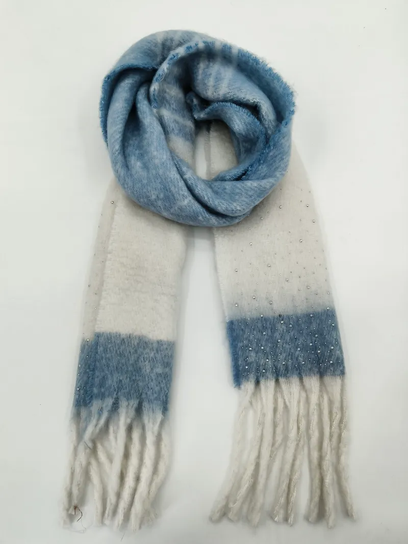 Weicher Winterschal in Blau-Creme-Karomuster mit aufgenähten Zierperlen und Fransenenden, spiralförmig auf hellem Hintergrund drapiert