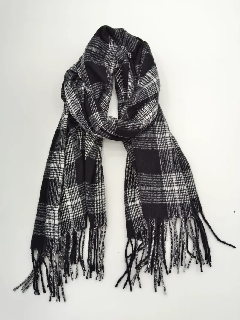Klassischer Tartan-Schal in Schwarz-Weiß mit geometrischem Karomuster und geknoteten Fransenenden, locker gefaltet auf weißem Untergrund