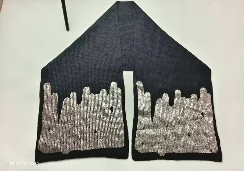 Schwarzer Strickschal mit glänzendem Silber-Metallic-Aufdruck in Tropfenoptik an beiden Schalenden, auf weißem Untergrund