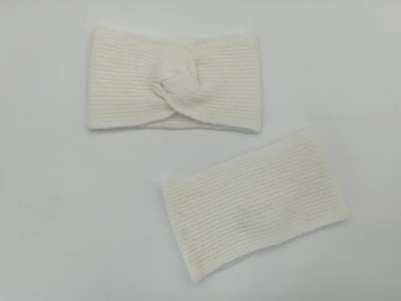 Creme geripptes Strick-Stirnband mit Twist-Knoten und passender Pulswärmer, flach auf weißer Oberfläche ausgelegt