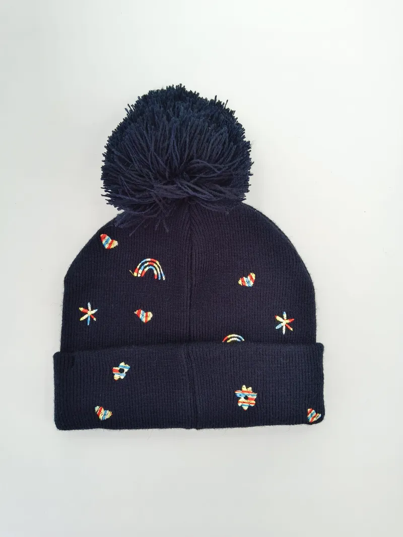 Dunkelblaue gerippte Wintermütze mit flauschigem Pompon und farbigen gestickten Regenbögen, Herzen, Sternen und Blumen