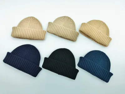Sechs gerippte Umschlagrand-Beanies in zwei Reihen angeordnet – in den Farben Beige, Dunkelblau, Schwarz und Stahlblau auf weißem Untergrund