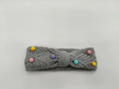 Grauer Strick-Schleifenstirnband mit pastellfarbenen Pompons in Gelb, Rosa, Lila und Türkis auf weißem Hintergrund