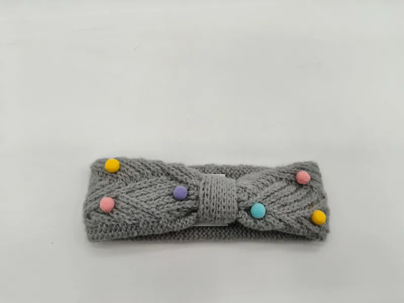 Grauer Strick-Schleifenstirnband mit pastellfarbenen Pompons in Gelb, Rosa, Lila und Türkis auf weißem Hintergrund