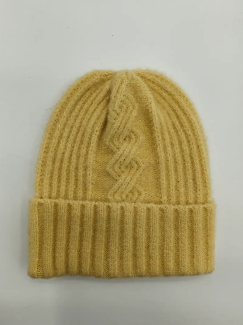 Buttergelbe gerippte Wollstrickmütze mit geometrischem Zopfmustermotiv und breitem Umschlagbündchen, flach auf weißem Hintergrund liegend