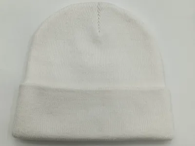 Weiße Strickmütze mit feinem Rippenmuster und gerolltem Bündchen, flach auf hellem Untergrund fotografiert, sichtbare Naht an der Spitze