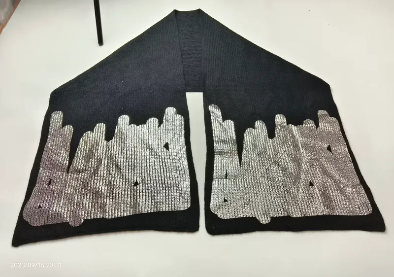 Schwarzer gestrickter Schal mit aufgedruckter silberner Stadtsilhouette an beiden Enden auf weißer Fläche