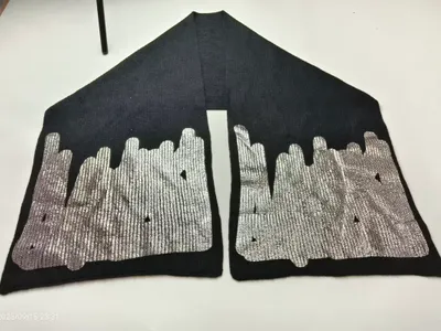 Schwarzer gestrickter Schal mit aufgedruckter silberner Stadtsilhouette an beiden Enden auf weißer Fläche