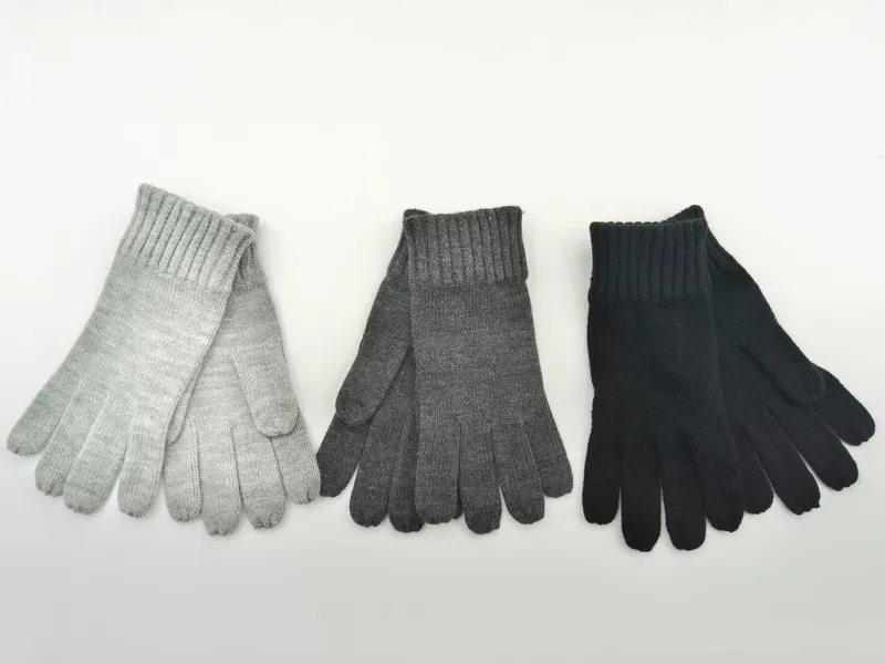 Drei Paar Rippenstrick-Winterhandschuhe in Hellgrau, Anthrazitgrau und Schwarz, flach auf weißem Untergrund ausgelegt