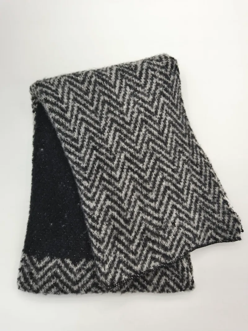 Gefalteter schwarz-grauer Strickschal mit Chevron-Zickzack-Muster und flauschiger Wollmischungs-Textur auf weißem Hintergrund