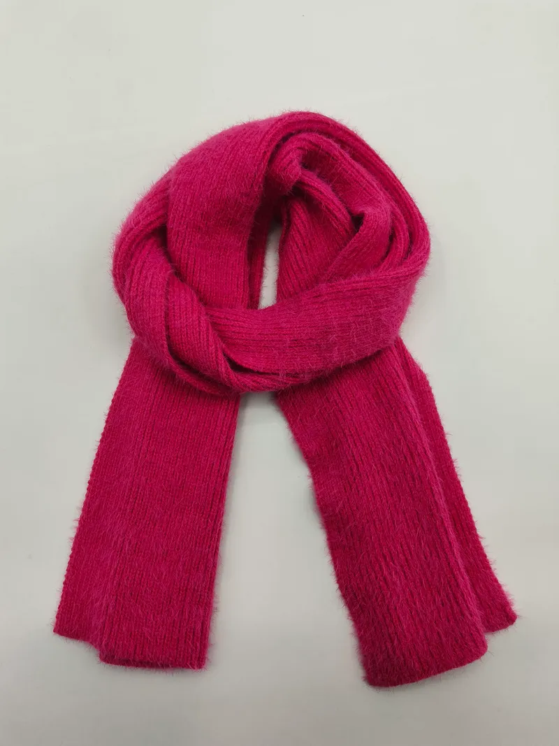 Leuchtend fuchsiafarbener Rippenstrickschal, zu einer Schlaufe gefaltet auf weißem Hintergrund, weiches flauschiges Garn sichtbar