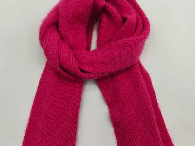 Leuchtend fuchsiafarbener Rippenstrickschal, zu einer Schlaufe gefaltet auf weißem Hintergrund, weiches flauschiges Garn sichtbar