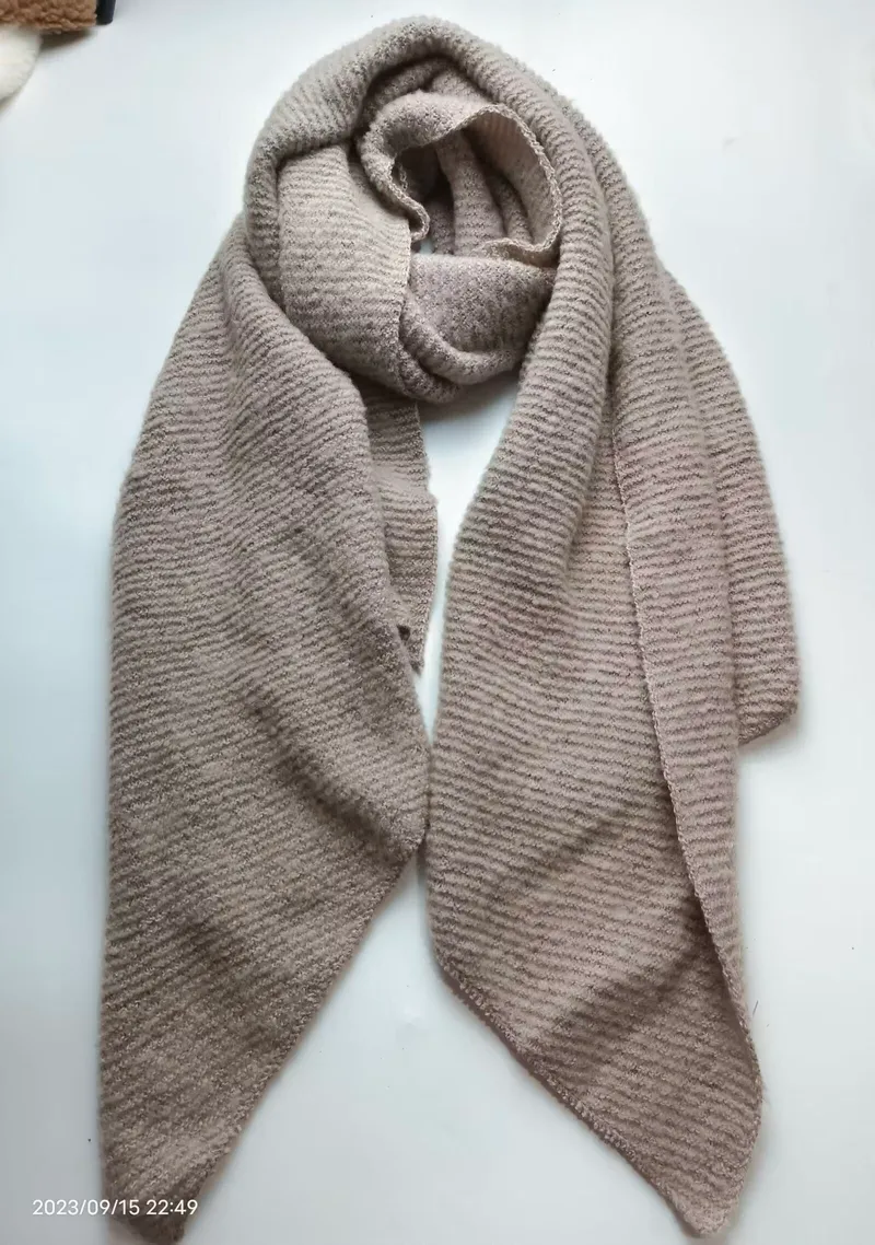 Beigefarbener Rippenstrick-Schal in Taupe als großzügige Wickeloption, Detailaufnahme der Streifentextur auf weißem Hintergrund