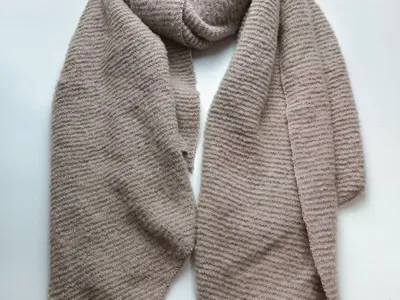 Beigefarbener Rippenstrick-Schal in Taupe als großzügige Wickeloption, Detailaufnahme der Streifentextur auf weißem Hintergrund