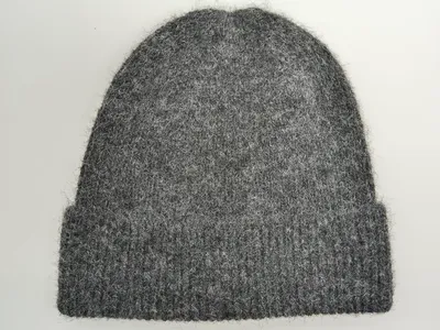 Weiche, flauschige Strickmütze in Grau mit breitem Rippenbündchen, flach fotografiert auf weißem Untergrund