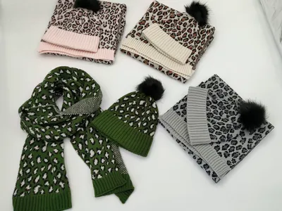 Vier Leopardenmuster-Mützen-und-Schal-Sets in Pink, Creme, Grün und Grau mit schwarzen Kunstfell-Pompons, auf weißer Fläche präsentiert