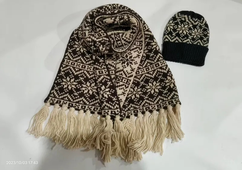 Braun-cremes Fair-Isle-Strickset bestehend aus Schal mit Fransenquasten und passender Schneeflocken-Beanie auf weißem Hintergrund